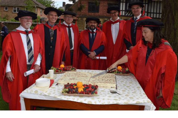 Graduates around the cake for cutting